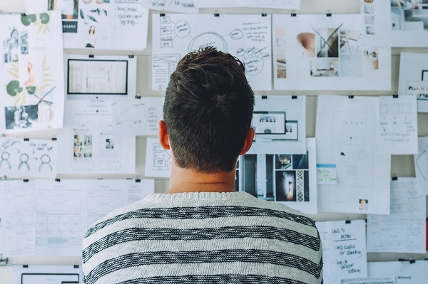 man in front of white board with writing