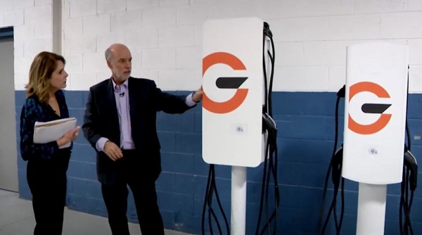 two people standing next to EV chargers