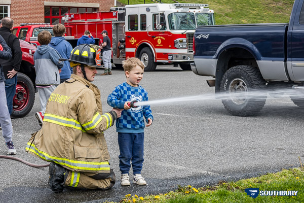 a boy with a firefighter spraying water to target